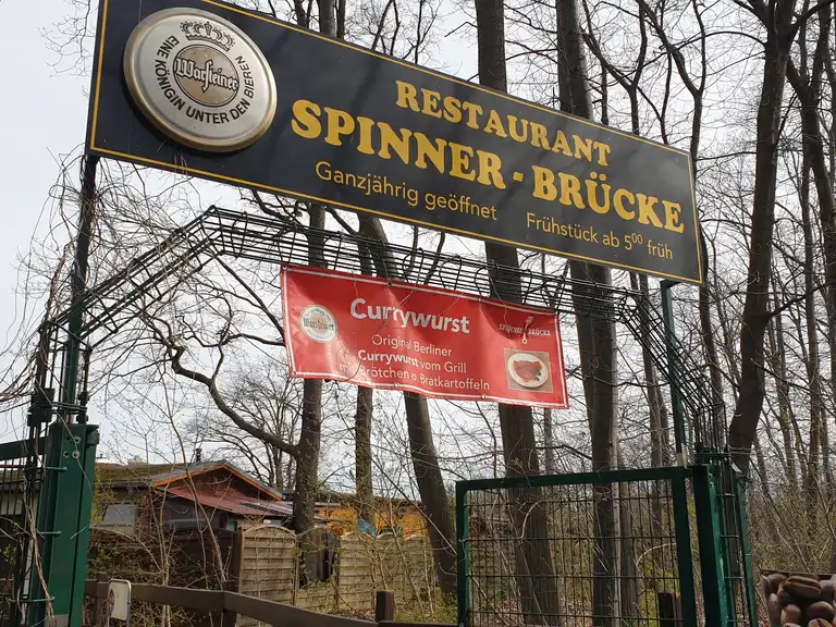 Eingangsschild des Restaurants Spinner-Brücke mit Currywurst-Banner