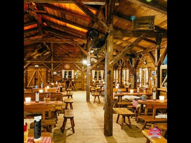 Rustikale Almhütte mit Holzbalken, gedeckten Tischen und Bänken