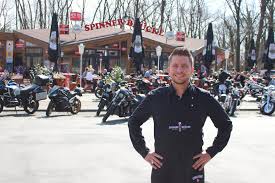 Florian Bernsteiner vor dem Gasthaus mit geparkten Motorrädern