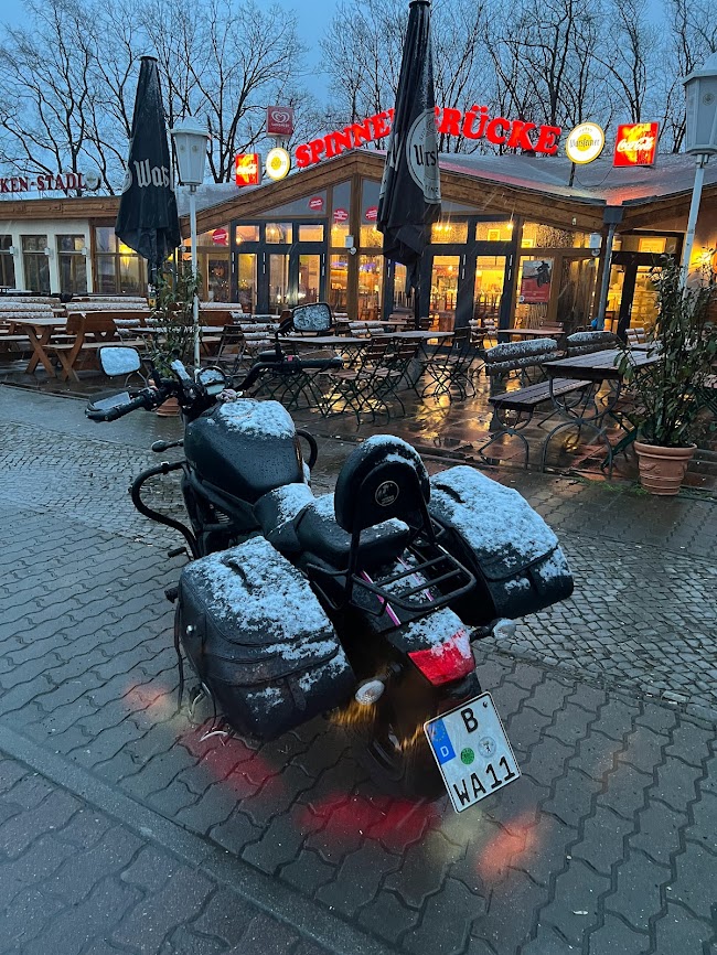 Verschneites Motorrad mit Beiwagen vor der abendlich beleuchteten Spinner-Brücke